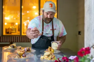 A chef sprinkling powder over a beautifully designed plate of food