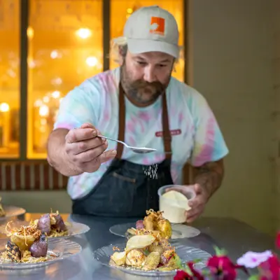 A chef sprinkling powder over a beautifully designed plate of food